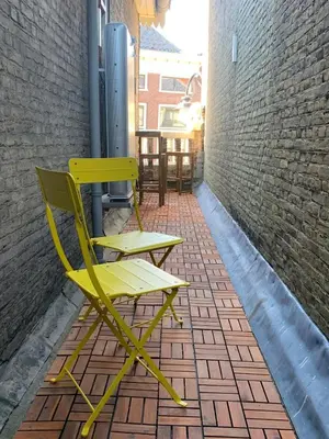 a yellow chair sitting on a brick patio at De Verwondering Privé etage met 2 slaapkamers in Gouda