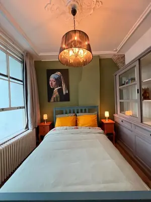 a bedroom with a large bed and a chandelier at De Verwondering Privé etage met 2 slaapkamers in Gouda