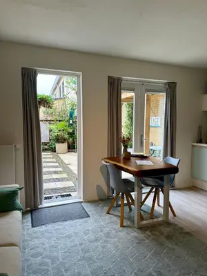 a dining room with a table and a door to a patio at Zeegroen in Zandvoort