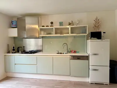 a kitchen with white cabinets and a white refrigerator at Zeegroen in Zandvoort