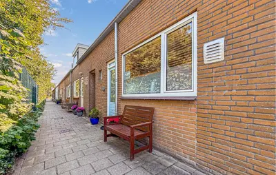 a row of benches sitting next to a brick building at 2 Bedroom Beach Front Home In Egmond Aan Zee in Egmond aan Zee