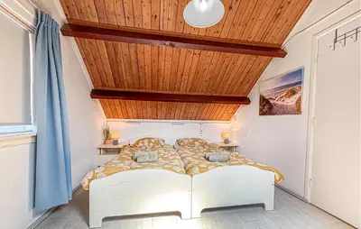 a bedroom with a white bed with a wooden ceiling at 2 Bedroom Beach Front Home In Egmond Aan Zee in Egmond aan Zee