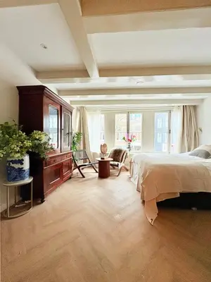 a bedroom with a bed and a dresser and windows at History and luxury in Amsterdam