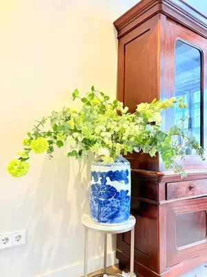 a blue and white vase sitting on a stool with a plant in it at History and luxury in Amsterdam