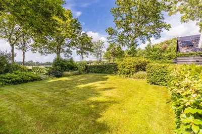an image of a garden with trees and grass at Puur Schoorl in Schoorl