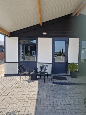 two chairs sitting outside of a building with a blue door at B&Boerderij De Veldmuis in Eemdijk