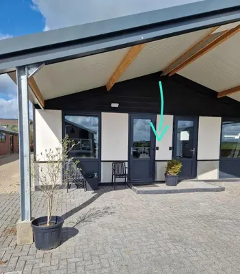 a black and white building with two potted plants at B&Boerderij De Veldmuis in Eemdijk