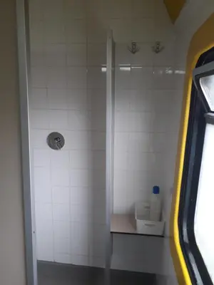 a shower in a bathroom with white tiles at Train Lodge Amsterdam in Amsterdam