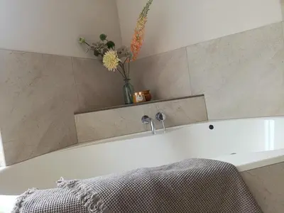 a bathroom with a bath tub with a vase of flowers at Mediterranean apartment with home theater in Bodegraven