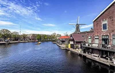 a river with buildings and a windmill in a city at Nice Home In Dirkshorn With Wifi in Dirkshorn