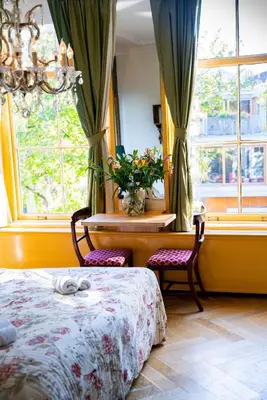 a bedroom with a bed and a table and windows at Boutique Hotel Museumkwartier in Utrecht