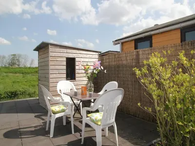 a patio with a table and chairs and a building at Pet-Friendly Bungalow in Warmenhuizen