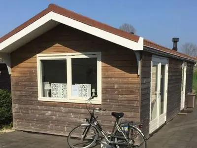 a bike parked in front of a small house at Pet-Friendly Bungalow in Warmenhuizen