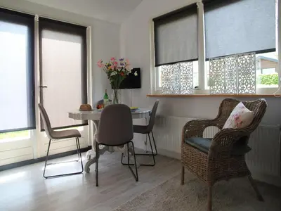 a living room with a table and chairs and windows at Pet-Friendly Bungalow in Warmenhuizen