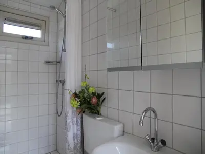 a white tiled bathroom with a sink and a shower at Pet-Friendly Bungalow in Warmenhuizen