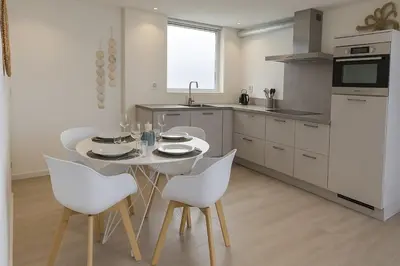 a kitchen with a white table and white chairs at Studio Noordwijk in Noordwijk