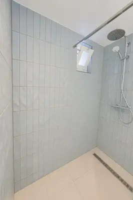 a bathroom with a shower with white tiles at Studio Noordwijk in Noordwijk