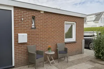 a patio with chairs and a table and a brick wall at Studio Noordwijk in Noordwijk