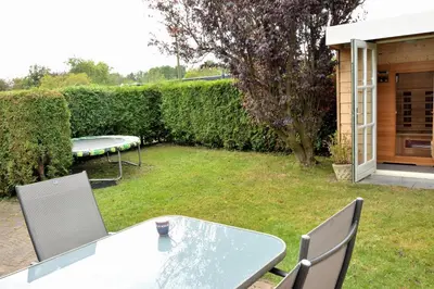 a table and chairs in a yard with a fence at Marinus, lovely bungalow near the sea and most beautiful dune area in the Netherlands in Warmenhuizen