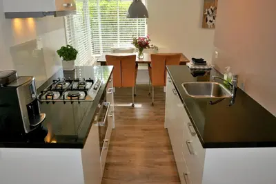 a kitchen with a sink and a stove top oven at Marinus, lovely bungalow near the sea and most beautiful dune area in the Netherlands in Warmenhuizen