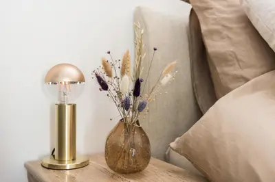 a vase with flowers on a table next to a bed at Ben Thuis Studio Alkmaar in Alkmaar