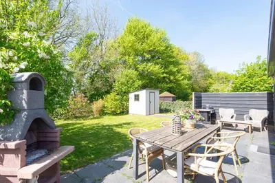 a patio with a wooden table and a fireplace at Duynhof nabij Strand, duinen, bos en stad - 5 personen in Warmenhuizen