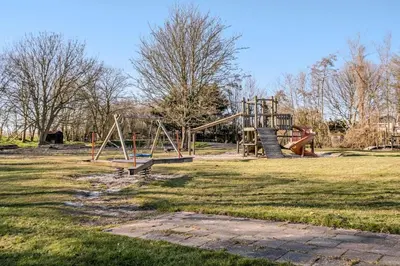a park with an empty playground in a field at Duynhof nabij Strand, duinen, bos en stad - 5 personen in Warmenhuizen