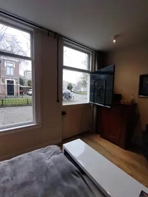 a living room with a large window and a flat screen tv at Park 43 in Haarlem