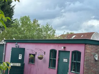 a pink building with a green door and windows at Vlinder 2pers studio in Utrecht