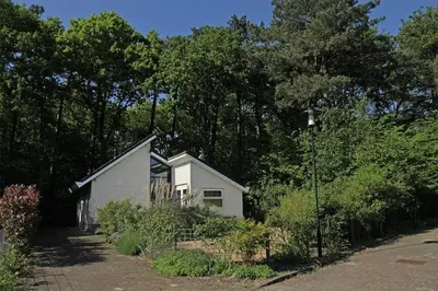 a small white house in front of some trees at Holiday Home in Schoorl near Dunes in Schoorl