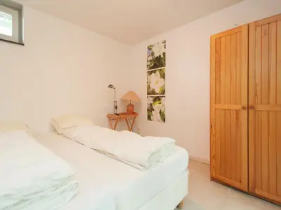 a bedroom with a bed with white sheets and a wooden door at Holiday Home in Schoorl near Dunes in Schoorl