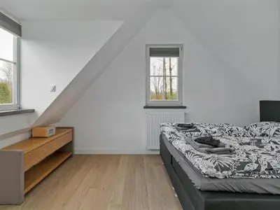 a bedroom with a bed and a dresser and two windows at Villa in Bosrijk near Horsterwold Forest in Zeewolde