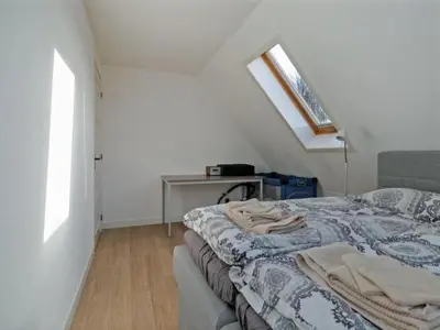 a bedroom with a bed and a table and a window at Villa in Bosrijk near Horsterwold Forest in Zeewolde