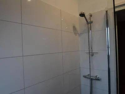 a shower in a bathroom with white tiles at Villa in Bosrijk near Horsterwold Forest in Zeewolde