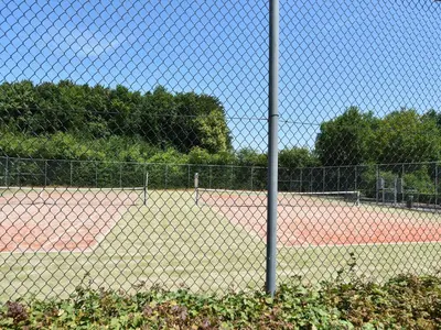 a tennis court seen through a chain link fence at Villa in Bosrijk near Horsterwold Forest in Zeewolde