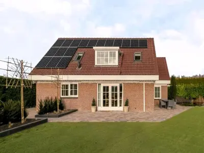 a brick house with solar panels on the roof at Villa in Bosrijk near Horsterwold Forest in Zeewolde
