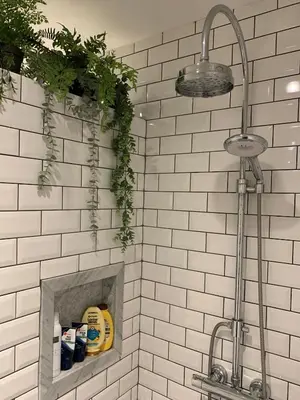 a bathroom with a white tiled wall with a shower at B&B Loft 57 in Amsterdam