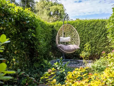 a wicker swing hanging from a hedge in a garden at Rekerlanden 1 in Warmenhuizen