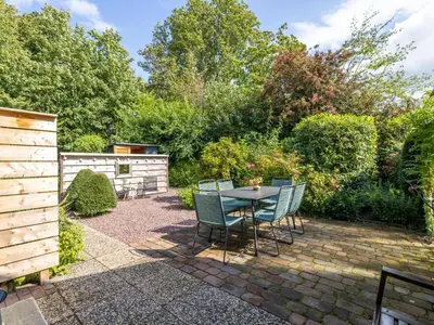 a patio with a table and chairs in a garden at Rekerlanden 1 in Warmenhuizen