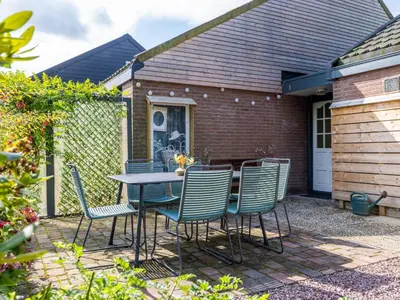 a patio with a table and chairs in front of a house at Rekerlanden 1 in Warmenhuizen