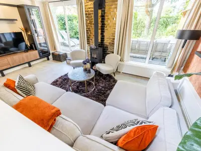 a living room with a white couch and orange pillows at Rekerlanden 1 in Warmenhuizen