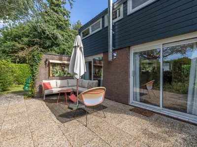 a patio with an umbrella and chairs and a couch at Rekerlanden 1 in Warmenhuizen