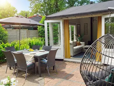 a patio with a table and chairs and a swing at Het Zonneschijnhuis in Dirkshorn