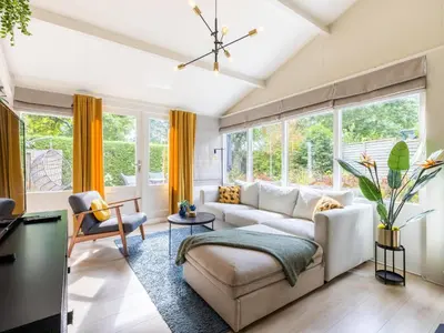 a living room with yellow curtains and a white couch at Het Zonneschijnhuis in Dirkshorn