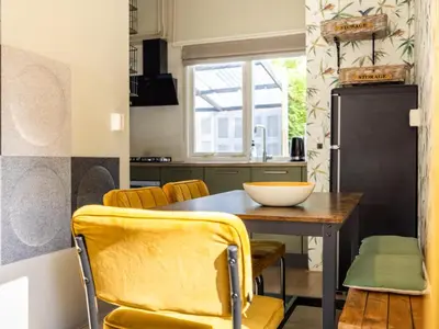 a kitchen with a wooden table and yellow chairs at Het Zonneschijnhuis in Dirkshorn