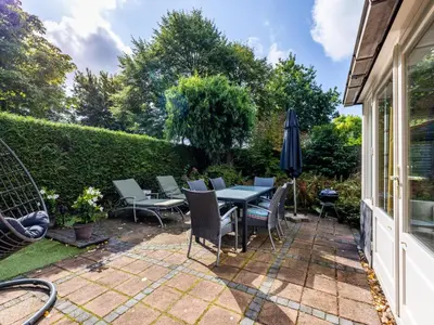 a patio with a table and chairs and an umbrella at Het Zonneschijnhuis in Dirkshorn