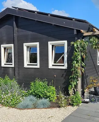 a black house with white windows and plants at De Fijne Blokhut in Nijkerkerveen