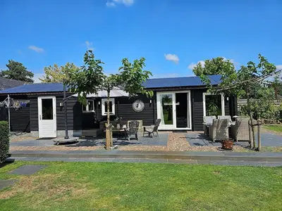 a black house with chairs and a table in front of it at De Fijne Blokhut in Nijkerkerveen