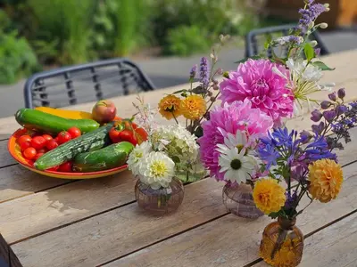 a wooden table with vases of flowers and vegetables at De Fijne Blokhut in Nijkerkerveen