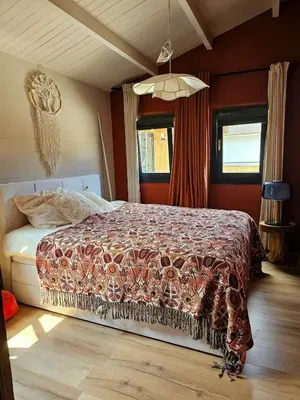 a bedroom with a bed with a comforter on it at De Fijne Blokhut in Nijkerkerveen